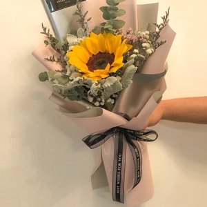 Close-up of yellow sunflower bouquet with pink wrapping and Best Wishes ribbon detail