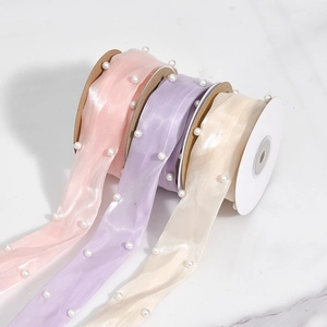 Detail view of pink, purple, and beige satin ribbons with elegant white pearl decorations