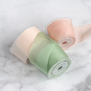 Close-up of three rolls of 4cm chiffon silk ribbons in Morandi pink, beige, and sage green