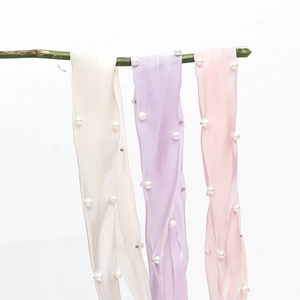 Detail of satin ribbons with pearl embellishments in cream, purple, and pink shades