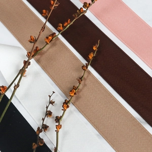 Gros plan de rubans en coton mat en rose, marron et kaki sur une surface en marbre