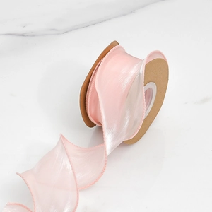 Détail du ruban en organza rose avec bordure ondulée sur fond de marbre