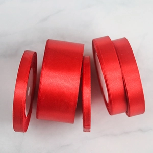 Detailed view of four different widths of glossy red satin ribbons for gift wrapping