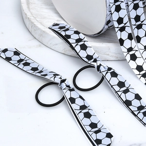 Macro detail of grosgrain ribbon with football print and black elastic hair tie set