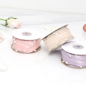 Three rolls of translucent mesh ribbons with pearl accents in pink beige and purple colors