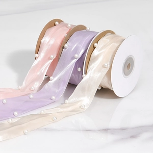 Close-up of elegant satin ribbons with embedded pearls in pink, purple and cream white tones