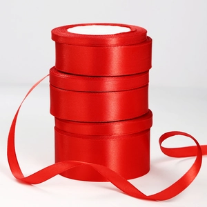 Three stacked rolls of vibrant red satin ribbon for gift wrapping and wedding decoration