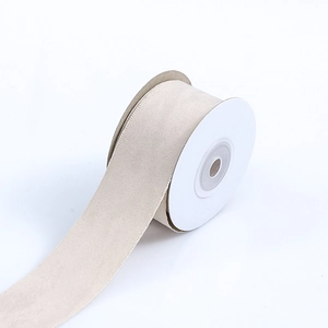 Macro detail of beige faux suede ribbon spool for DIY bow making and crafts