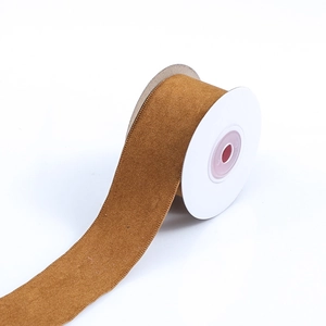 Macro shot of tan suede ribbon roll for DIY crafts on a white plastic spool