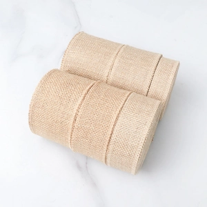 Two rolls of natural jute burlap ribbon with stitched edges on a white marble surface