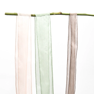 Frayed edge silk chiffon ribbons in soft pink, green, and mauve hanging on a natural branch
