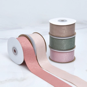 Detail of assorted velvet satin ribbons in pastel tones on a marble surface for DIY gifts