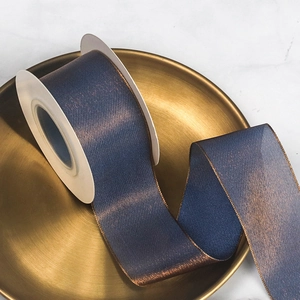 Close-up of chameleon organza ribbon with blue and gold shimmer on metallic tray