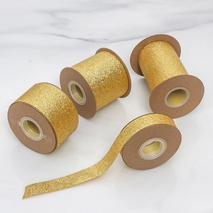 Macro shot of glittery gold ribbons on kraft spools for DIY gift bows and crafts
