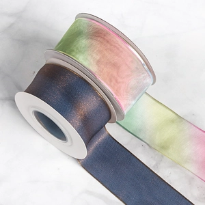 Gradient organza ribbon and metallic satin rolls on marble for DIY gift wrapping