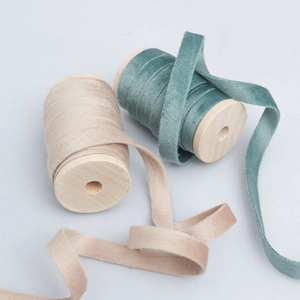 Detail of 1cm double-sided velvet ribbons in champagne and teal on wooden spools