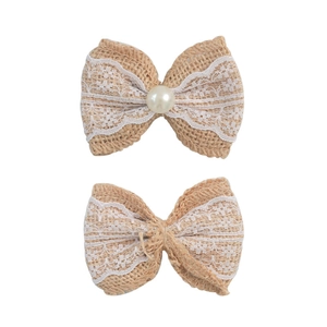 Detail of handmade jute bow with white lace edge and pearl bead in rustic style