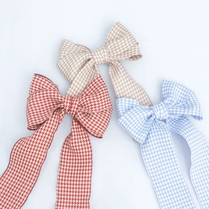 Detailed close-up of three houndstooth pattern bow hair clips in red, blue, and brown
