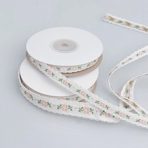 Detail of floral embroidery ribbon rolls with pink flower pattern for DIY crafts