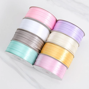 Top view of eight colorful 3mm satin ribbon rolls on a clean marble surface for DIY crafts