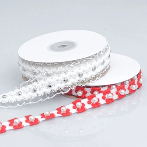Detailed view of embroidered red flowers and pearls on white lace ribbons for DIY decor