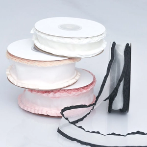 Close-up of ruffled organza ribbons in white, pink, and champagne on paper spools
