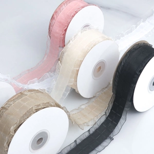Vue macro de rubans en organza plissés à carreaux en rose, beige, doré et noir sur bobines