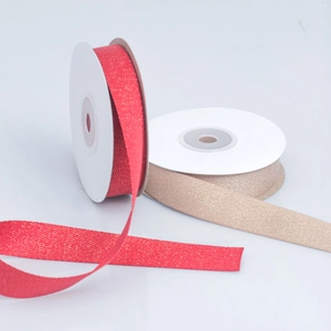 Close-up of red and champagne herringbone ribbons with gold glitter on white rolls