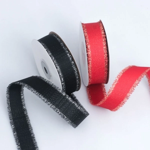 Macro detail of grosgrain ribbon with metallic frayed edges in black and red colors