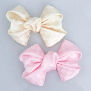 Detailed view of handmade bow hairpins with cream and pink checkered satin fabric texture