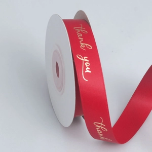 Macro detail of red satin ribbon roll with gold thank you print for gift wrapping