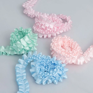Close-up of 2.5cm ruffled polyester ribbons in pastel pink, blue and mint for DIY crafts