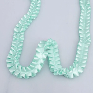 Detailed close-up of mint green pleated polyester ribbon with a silky satin luster