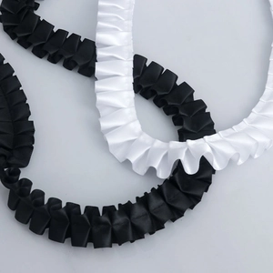 Detail view of 2.5cm pleated polyester lace trim in classic black and white satin