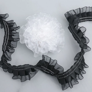 Macro detail of 4cm black pleated organza lace and white fabric flower for DIY sewing