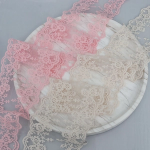 Detail of 13cm embroidered floral lace trim in pink and beige on marble plate