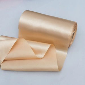 Close-up of champagne gold satin ribbon roll showing smooth texture and silky glossy finish