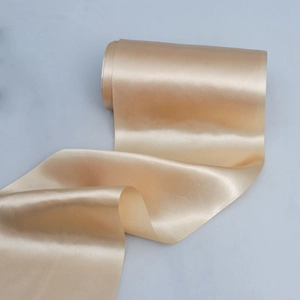 Close-up of champagne gold satin ribbon with glossy texture for wedding chair back decoration