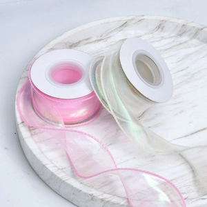 Macro view of iridescent organza ribbon rolls in pink and white on marble tray