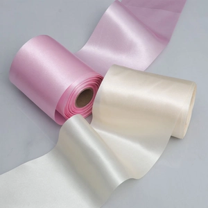 Close-up of pink and cream satin ribbons with smooth silky texture and glossy finish