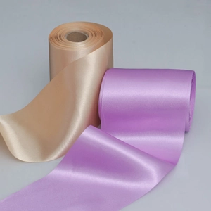 Close-up of champagne and lilac satin ribbons showing high-gloss texture and neat edges