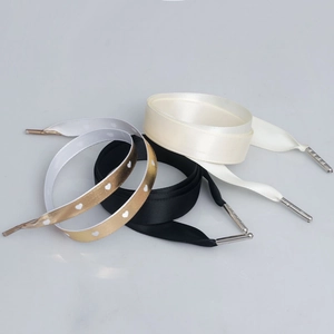 Nahaufnahme von Satin-Schnürsenkeln in Creme, Schwarz und Gold mit Herzmustern und Metall