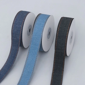 Detail of denim ribbons with orange stitching in blue and black colors on white rolls