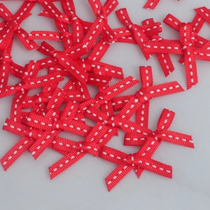 Macro detail of red 6mm ribbed grosgrain ribbon bows with white stitching for DIY crafts