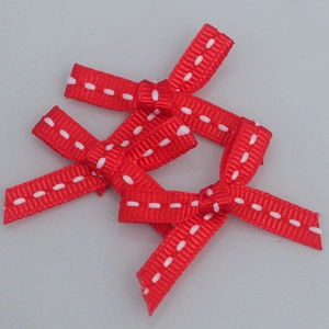 Close-up of three red ribbed ribbon bows with white stitched lines for DIY crafts