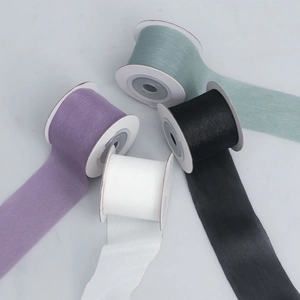 Close-up of four rolls of sheer organza ribbon in purple, green, black and white