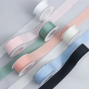 Detailed view of colorful matte polyester ribbons neatly wound on white spools for DIY