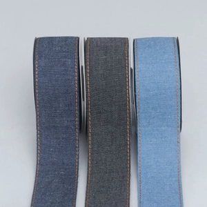 Three rolls of denim fabric ribbons in blue and grey with orange contrast stitching edges