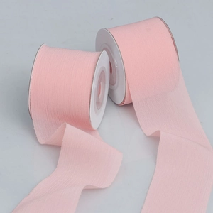 Detail of two rolls of pink sheer chiffon ribbons with elegant pleated textures for DIY crafts