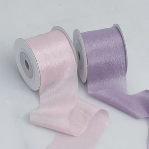 Close-up of light pink and purple pearlescent chiffon ribbons on white plastic spools
